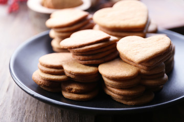Heart shaped biscuits on plate with ash berry on wooden background