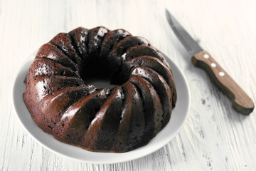 Chocolate cake on plate on white wooden background, top view