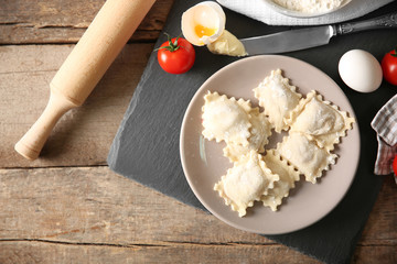 Uncooked ravioli on plate on wooden table