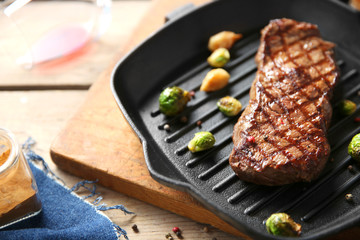 Grilled steak with garlic and Brussels sprouts on grill pan, closeup