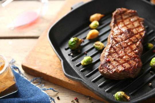 Grilled steak with garlic and Brussels sprouts on grill pan, closeup