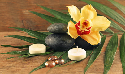 Spa stones with beautiful flowers and candles on wooden background