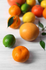 Fresh citrus fruits with green leaves on wooden background