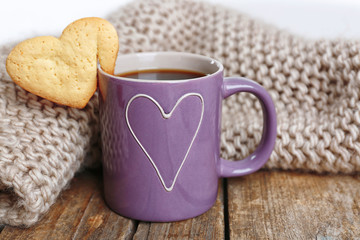 Heart shape cookie on cup of coffee on wooden table closeup