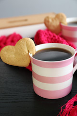 Heart shape cookie on cup of coffee on wooden table closeup
