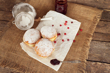 Delicious donuts with jam on parchment and sackcloth closeup