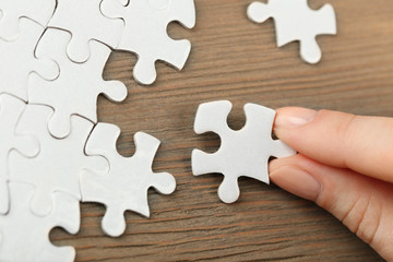 Woman playing with jigsaw puzzle on wooden table