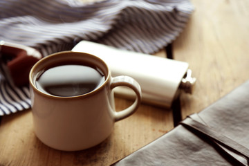 Cup of strong coffee with a flask on a wooden table, close up