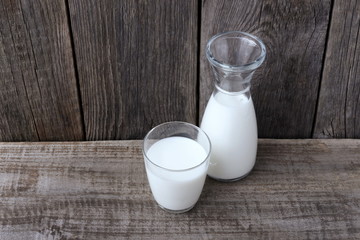 the glass and the bottle of milk on the old table