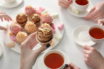 Tea Party with sweet creamy cakes over wooden table background