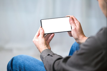 hands man holding mobile phone in the living room / Man using smartphone in the room of home 