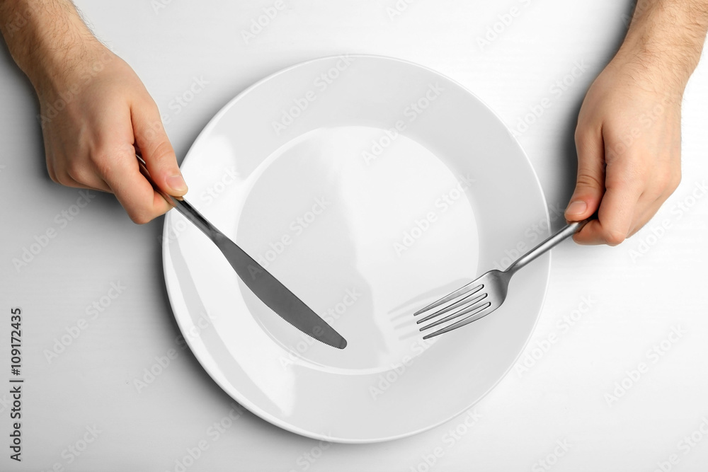 Wall mural male hands holding silver cutlery over plate, isolated on white