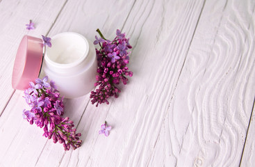 Obraz na płótnie Canvas Pot of moisturizing cream with lilac flowers