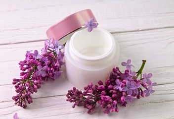 Fototapeta na wymiar Pot of moisturizing cream with lilac flowers
