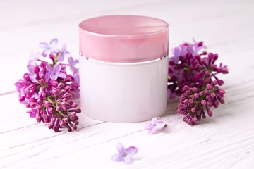 Fototapeta na wymiar Pot of moisturizing cream with lilac flowers