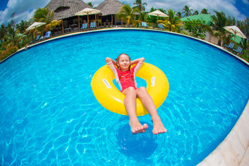 Little girl with inflatable rubber circle having fun in swimming pool