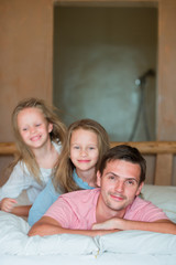 Father with two adorable little girls having fun in bed 