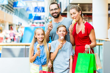 Family eating ice cream in shopping mall with bags