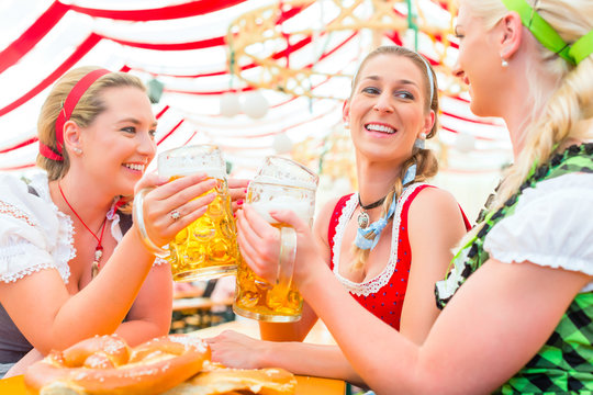 Freundinnen trinken zusammen Bier im Bayrischen Dirndl auf Volksfest