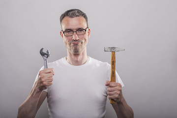 Man with adjustable spanner and hammer