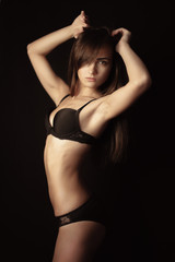 Fototapeta na wymiar Shot of a sexy woman in black lingerie over black background.