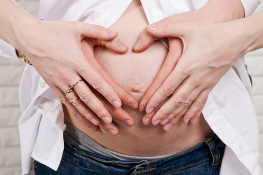 pregnant woman's belly with hands and heart
