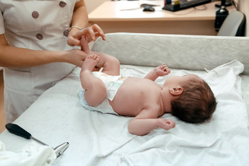 Pediatrician examining littlle newborn baby on the table