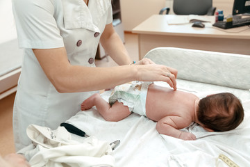 Pediatrician examining littlle newborn baby on the table