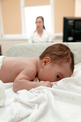 Little newborn baby lying on the table in doctor's  office
