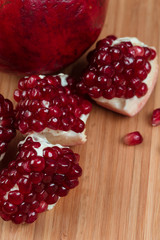 Several pieces of juicy pomegranate on the wooden board