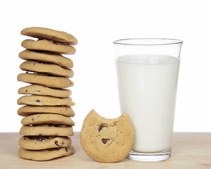 Stack of 12 chocolate chip cookies next to a glass of milk