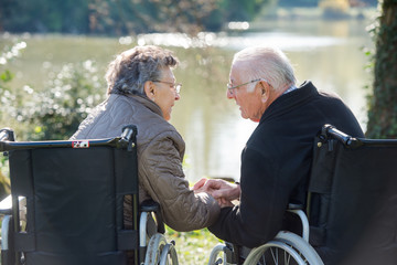Couple in wheelchairs holding hands