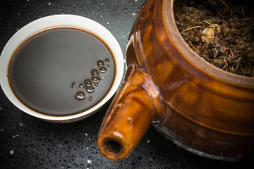 bowl of Chinese herbal tea and an enamel pot with herbs nearby