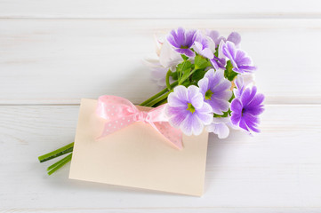 Bouquet of violet primroses and paper greeting card