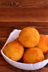 Arancini balls on a plate. Homemade dinner fried rice cutlets recipe. Close-up. Brown wooden background