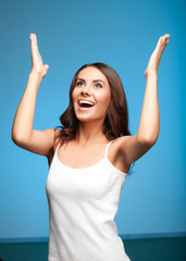 Happy gesturing woman looking up, over blue