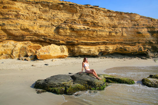 Young woman in bikini sitting at La Mina Beach in Paracas Nation