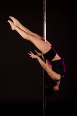 Young sexy pole dancer on black background