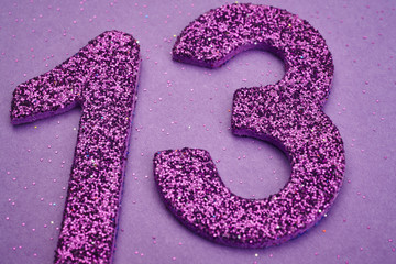 Number thirteen purple color over a purple background. Anniversa