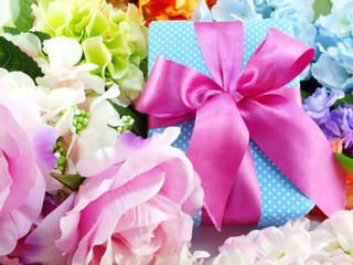 gift box present with pink ribbon bow and beautiful colorful flowers background