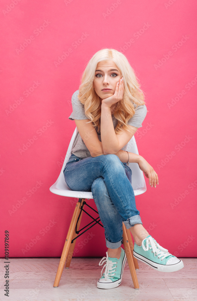 Wall mural Sad young woman sitting on the chair