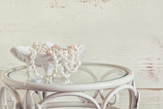 high key image of white pearls necklace on vintage table