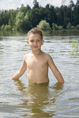 Summer bright sunny day boy is bathed in the river.