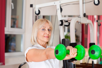 Fototapeta premium Close-up of aged woman doing exercise with set of weights