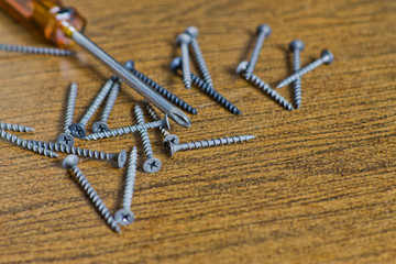 screws and screwdriver on a wooden background