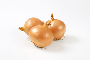 three raw onions on white background