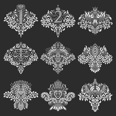 Set of ornamental elements for design in coats of arms form. White floral decorations on black. Isolated tattoo patterns in vintage baroque style.