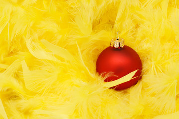 Rote Weihnachtskugeln auf gelben Federn