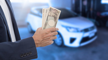 Businessman hand holding Japanese banknote with blur car backgro