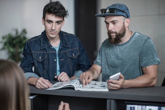 Two young men making query at office reception
